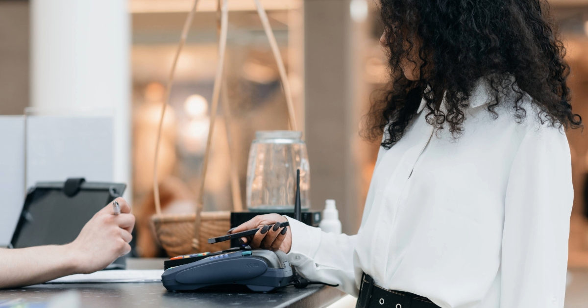 Young woman using her smartphone for contactless payment in a cafe 