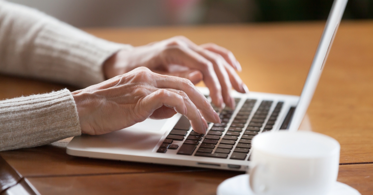 Mature female person typing text on keyboard