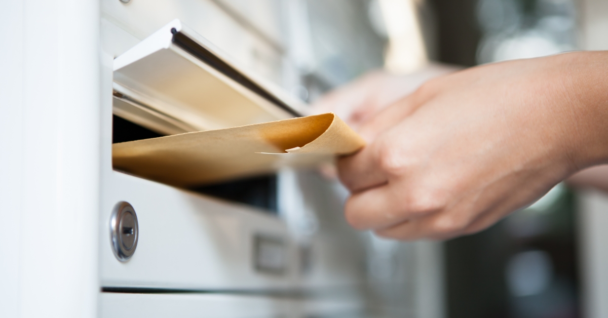 woman putting envelope in mailbox 