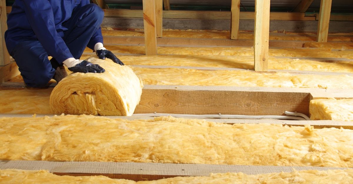 worker thermally insulating house attic with glass wool 