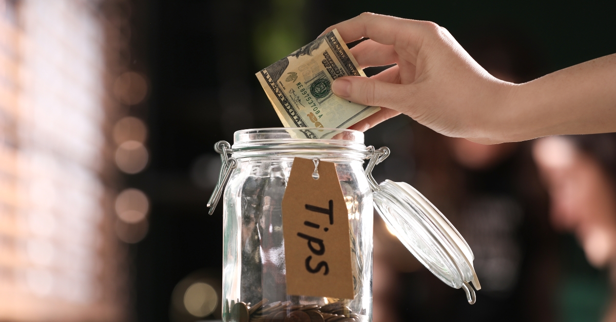 woman putting tips into glass jar