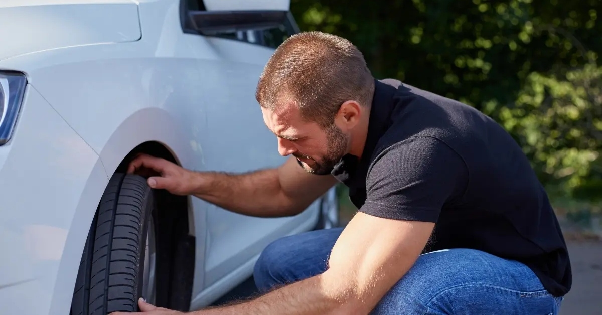 examining tires on his car