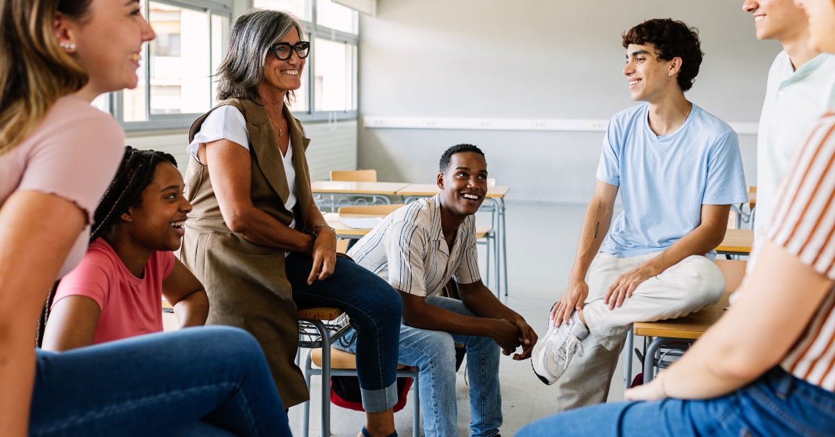 group of high school students talking with mature teacher