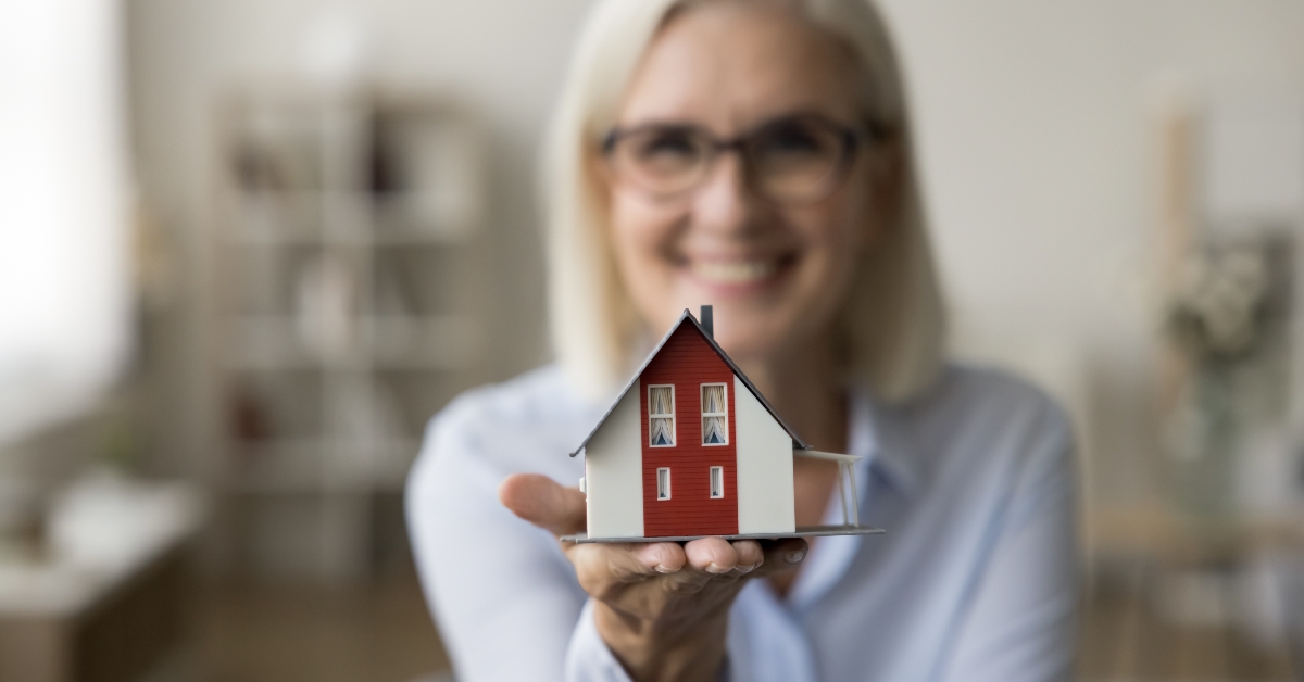 tiny house model on hand of real estate agent woman