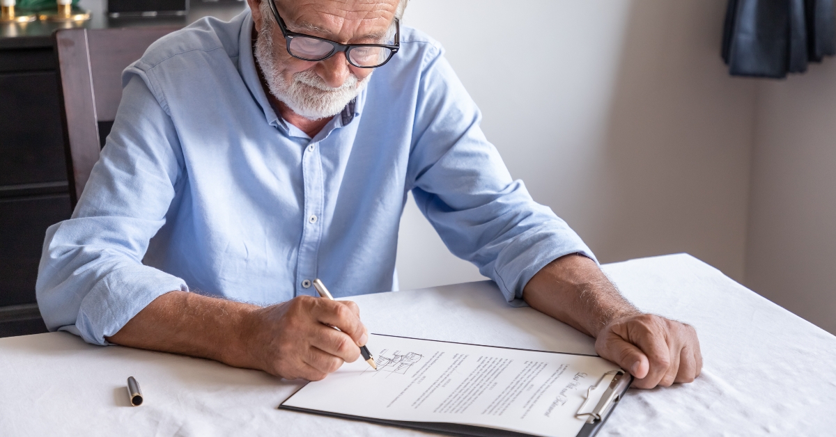 Senior man examining and signing last will