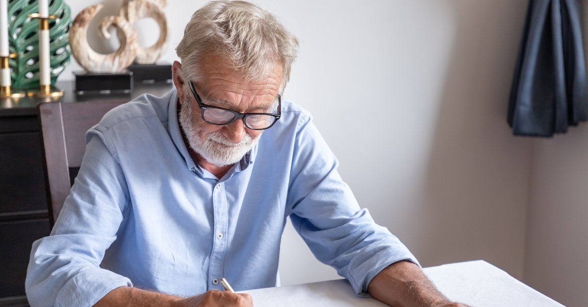 senior old man elderly examining and signing last will and testament