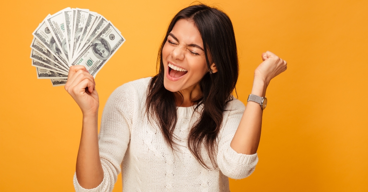portrait of a cheerful young woman holding money