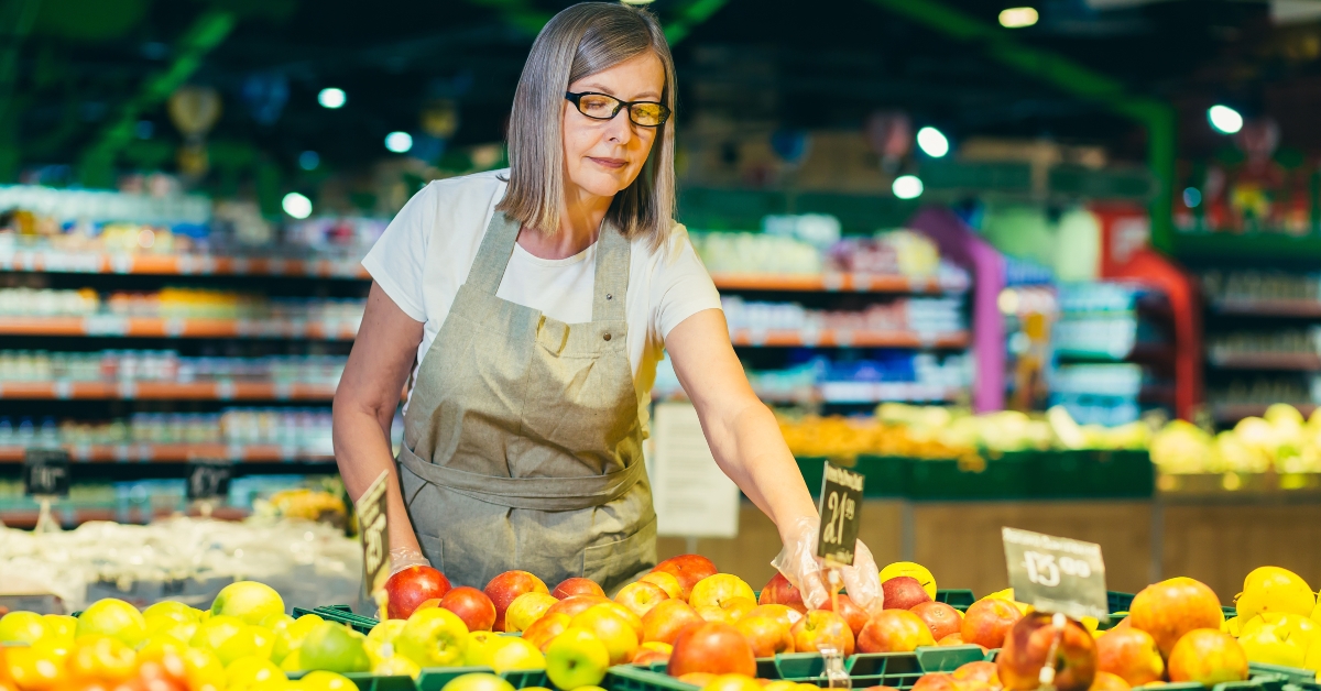 store worker lays out and sorts fruit