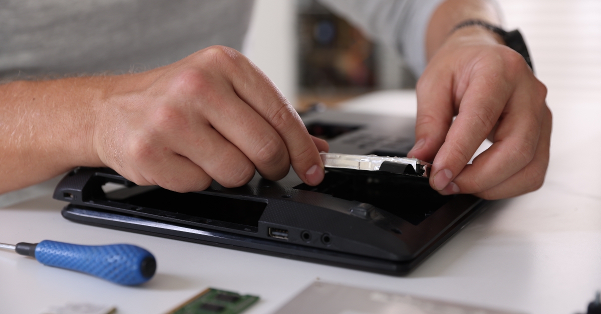 Man fixing old laptop at white table