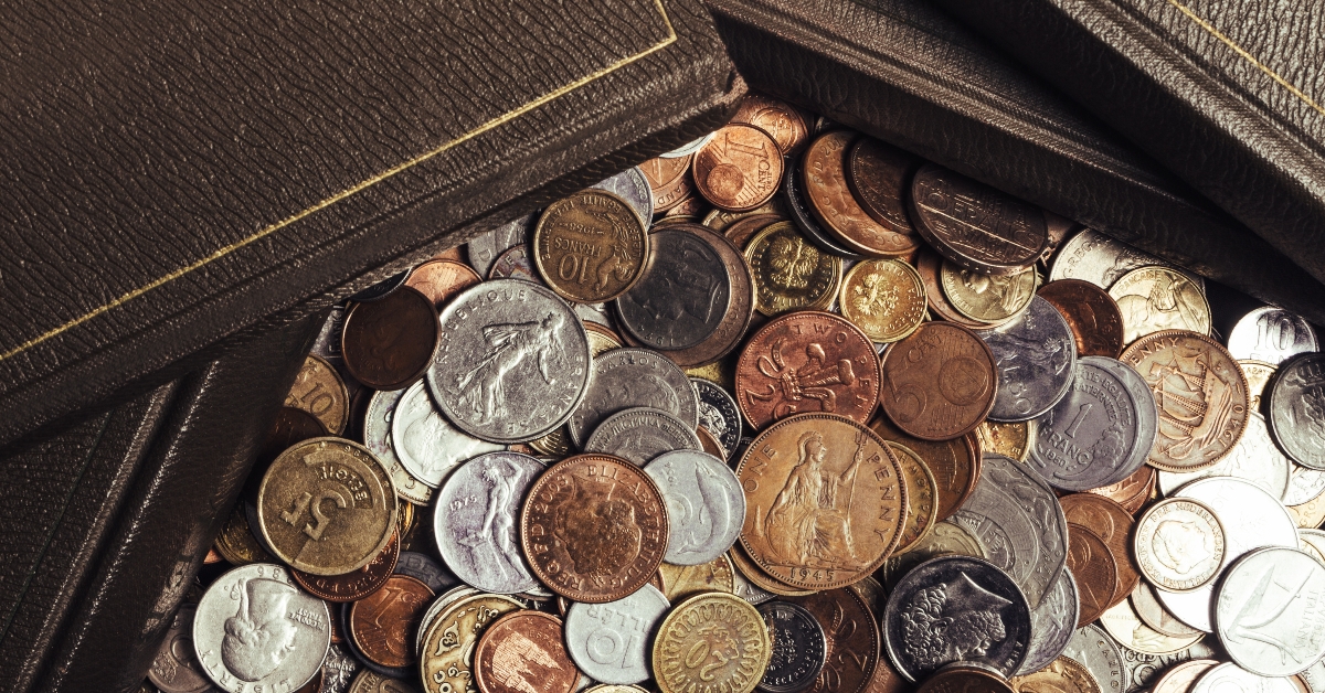 old books laying on scattered pile of world coins