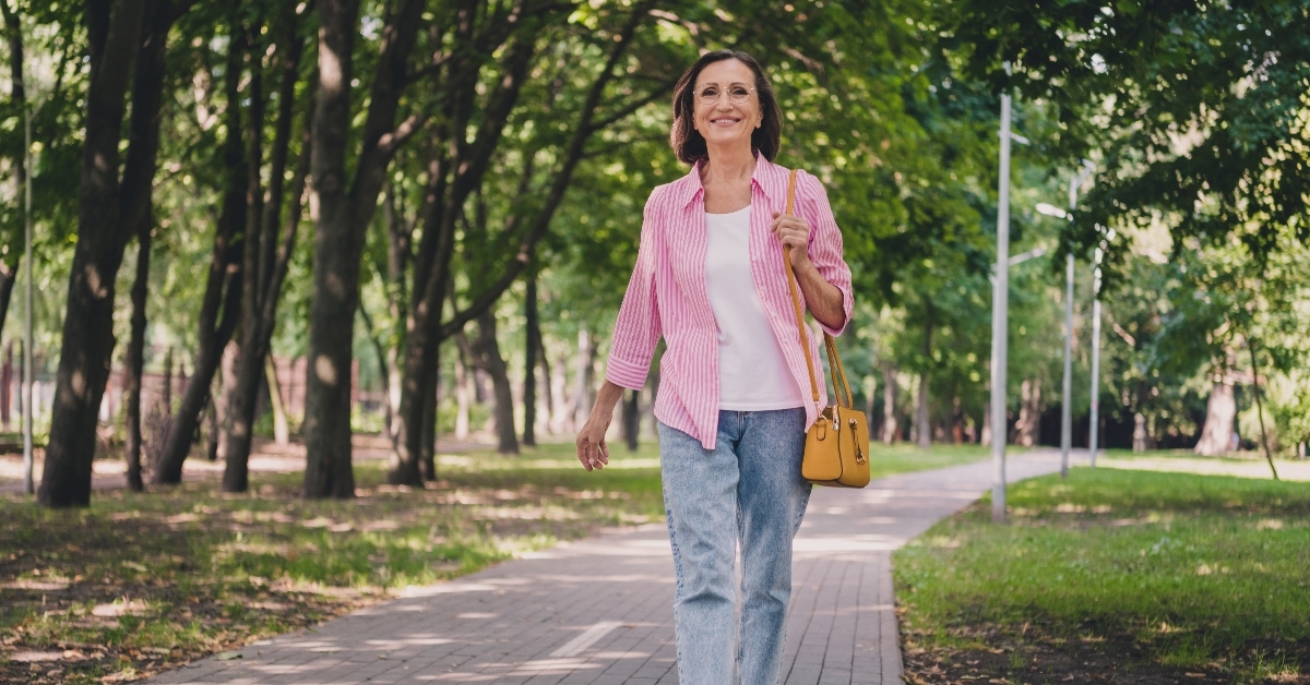 older woman walking in the park smiling 