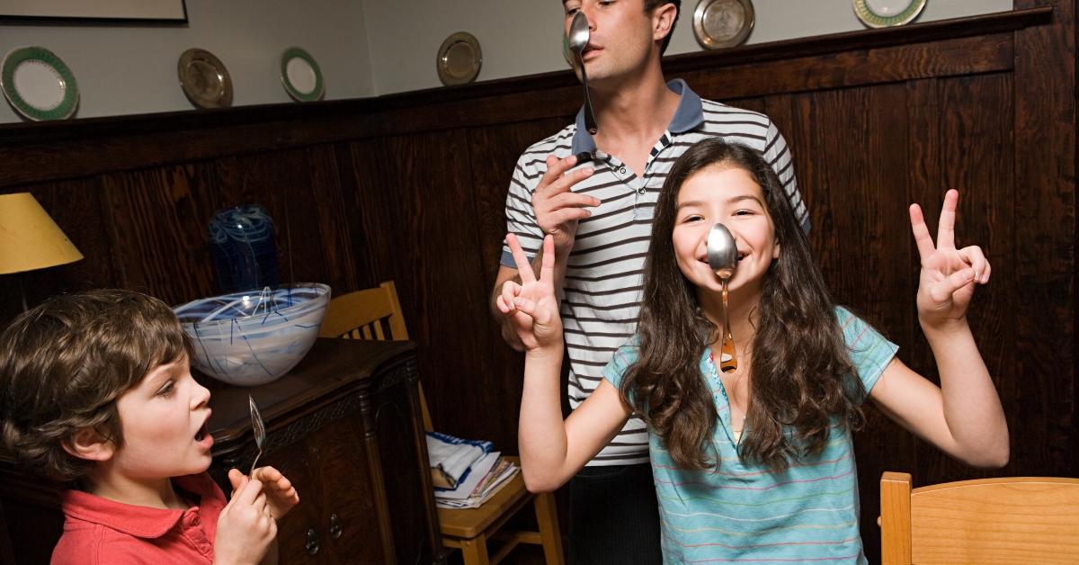 father and his children hanging spoons on their noses 