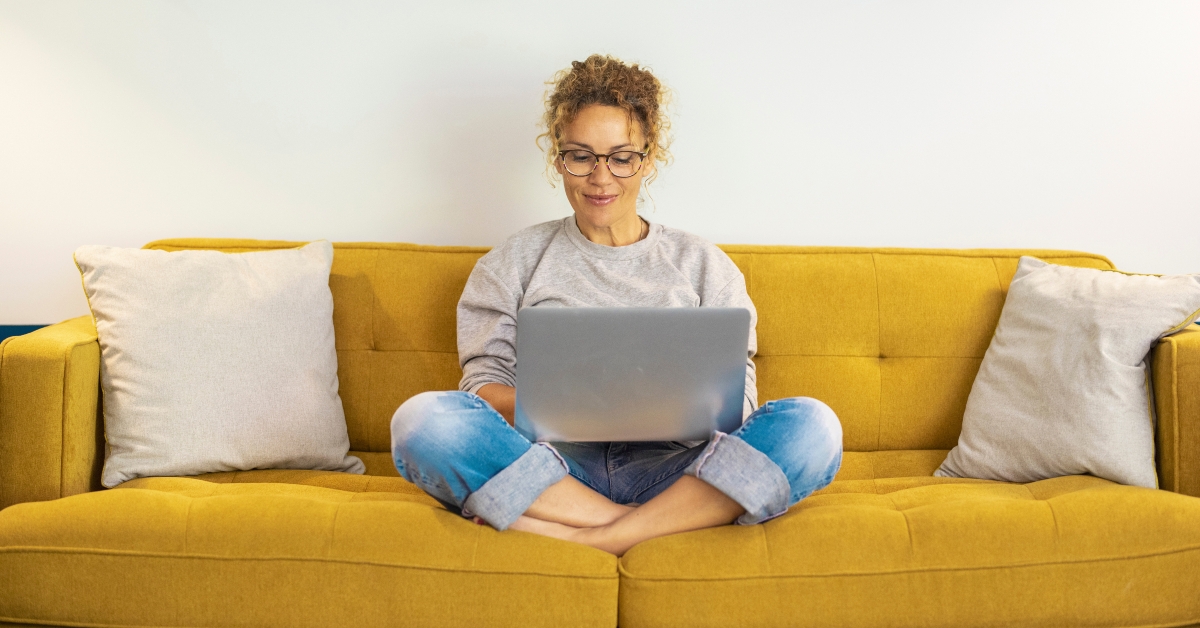 using laptop on a yellow sofa