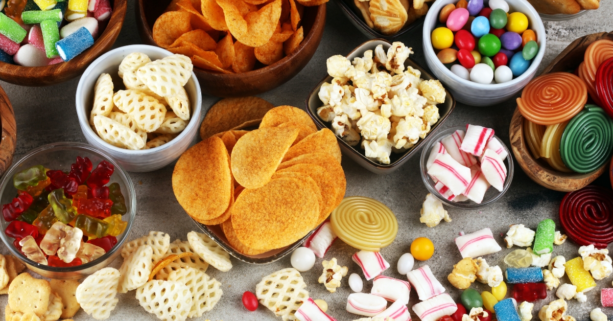 Salty snacks. Pretzels, chips, crackers and candy sweets on table 