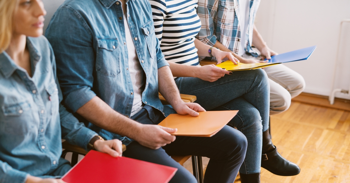 people sitting in chairs with folders before the job interview