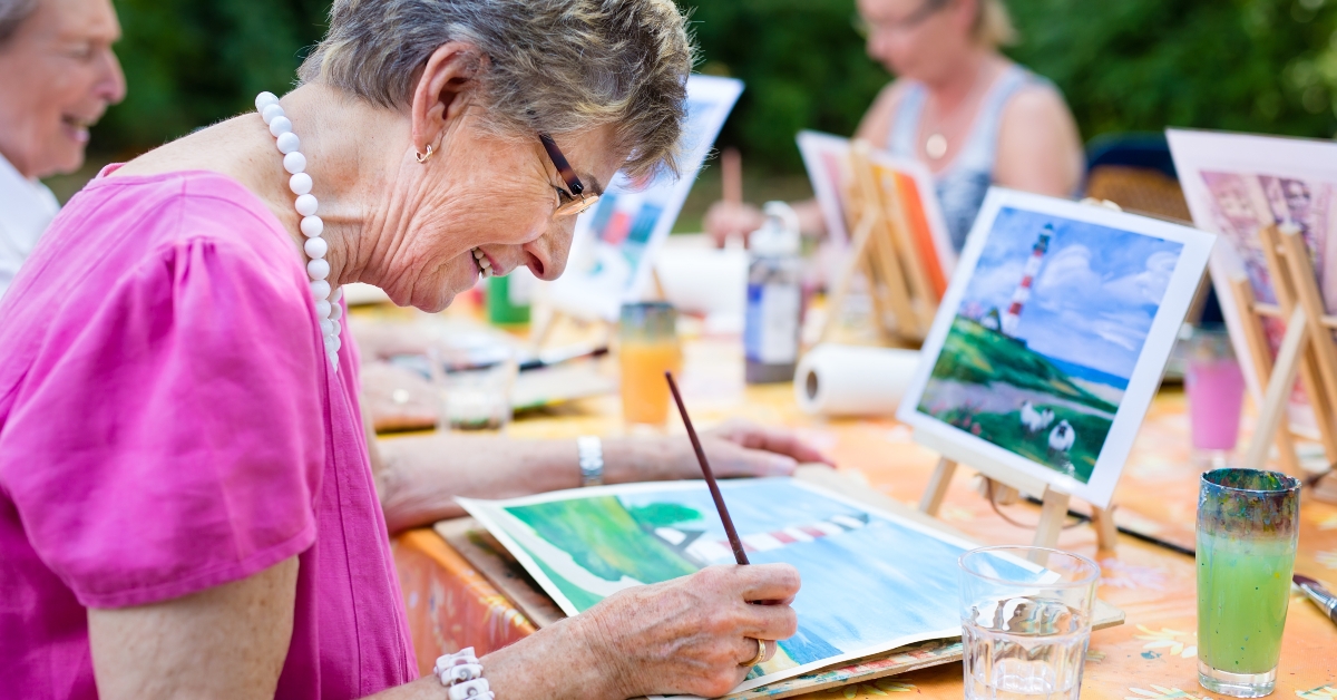 senior woman smiling while drawing with the group