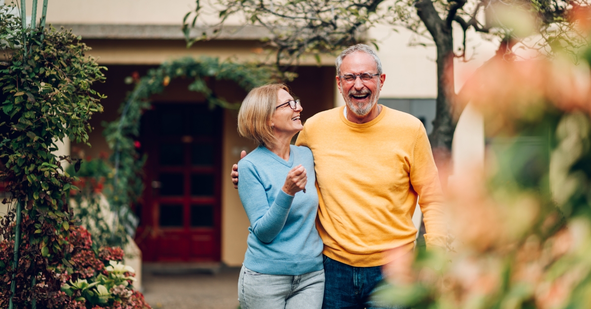 Senior couple holding keys and standing outside
