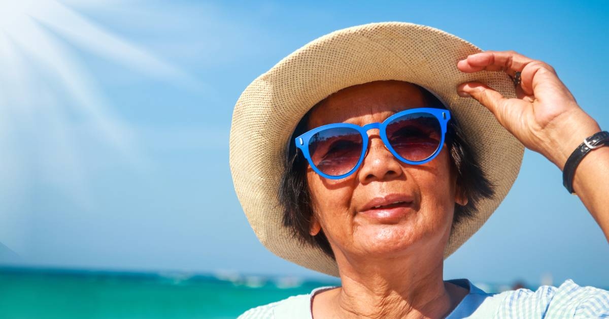 woman enjoys fun, visiting the sea, wearing a hat and wearing blue sunglasses