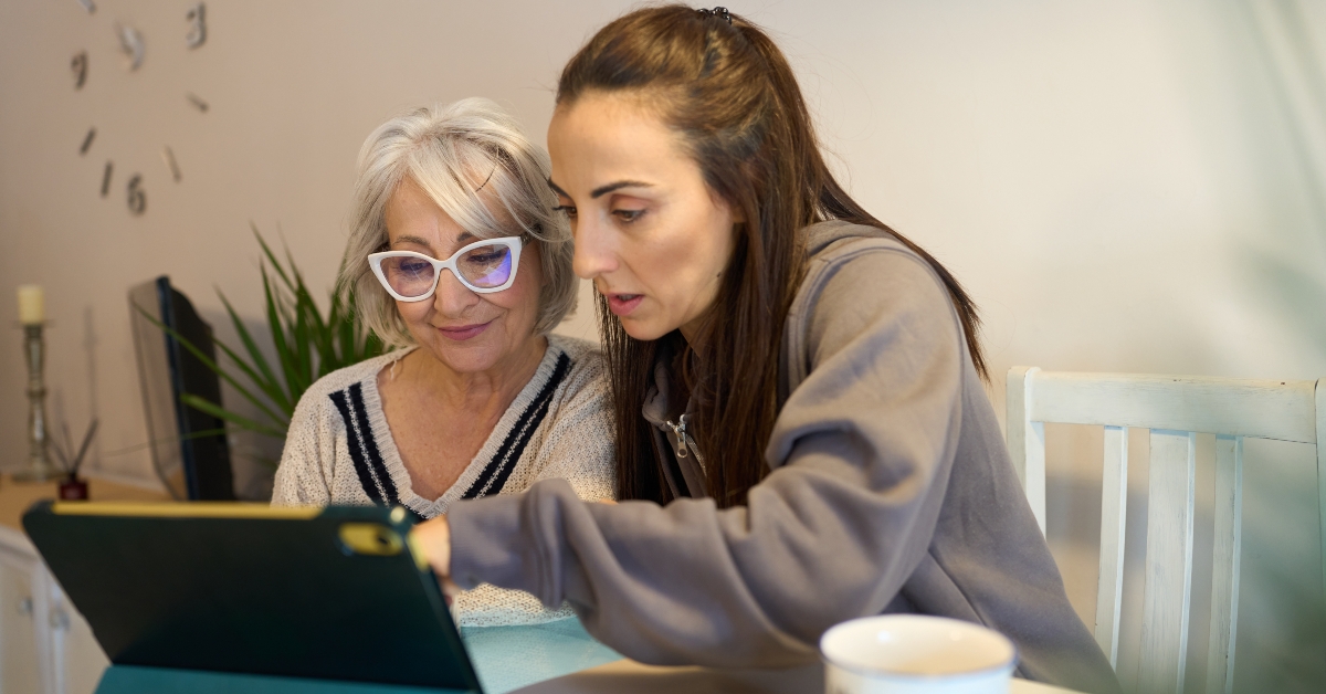 woman helping senior mother using digital tablet