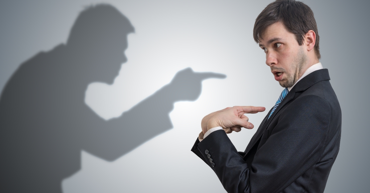 Shadow of man is pointing and blaming businessman