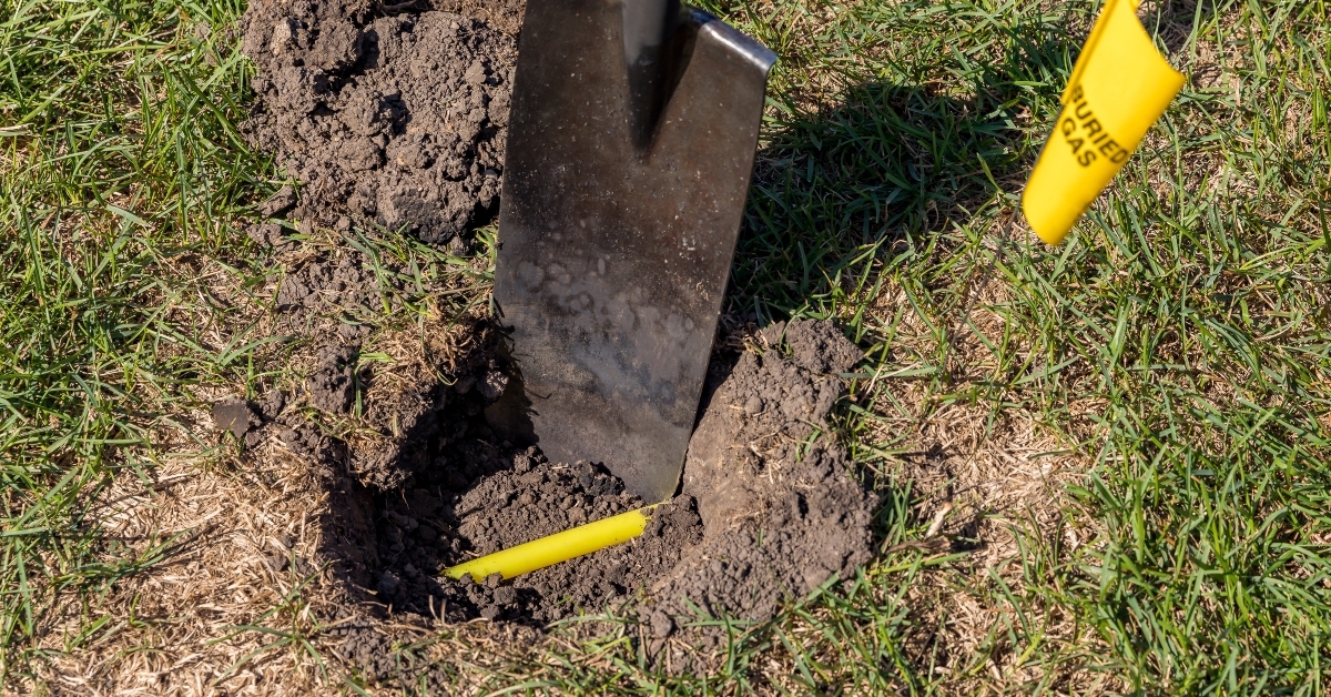 shovel in soil and yellow buried gas