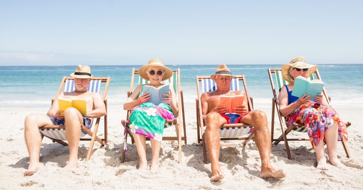 Senior friends reading books on beach chair 