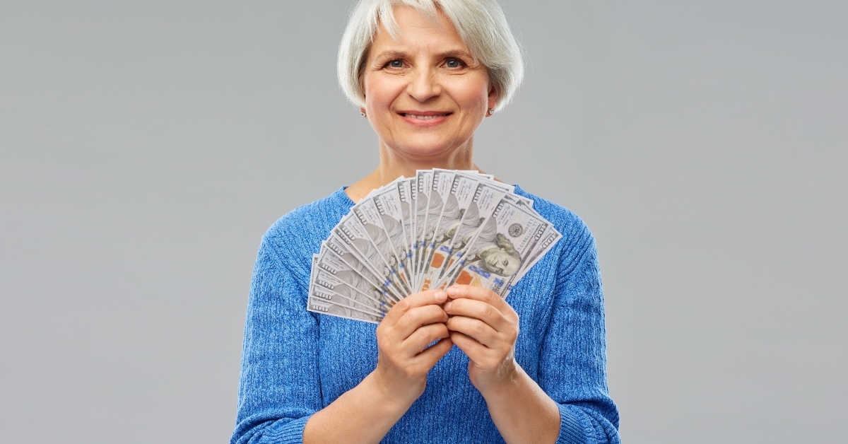senior woman holding hundreds of dollar money