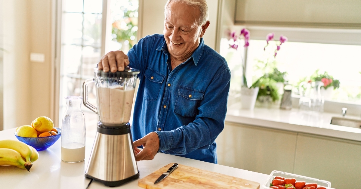 senior man smiling confident shaking blender