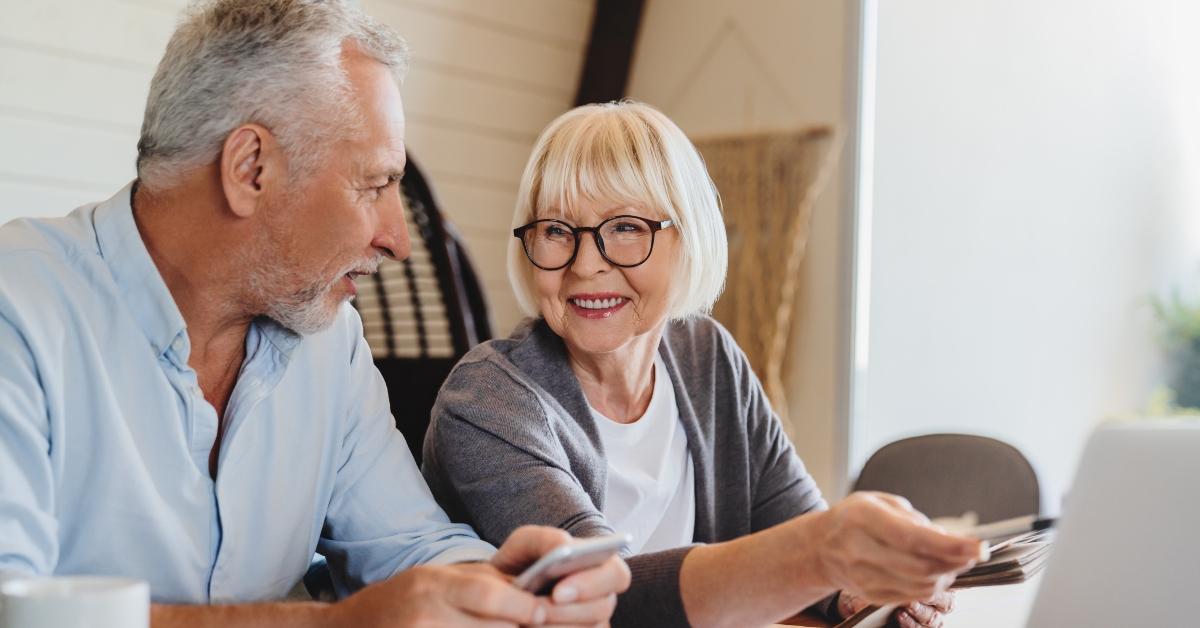 wife and husband sit on couch using computer