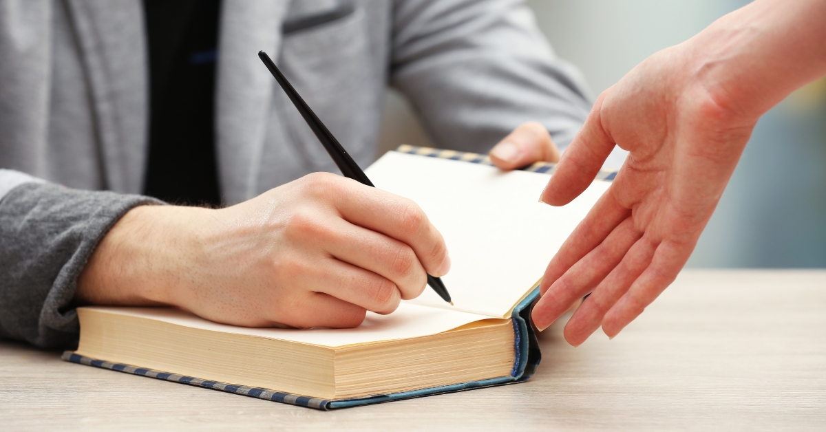 Author signing autograph in own book