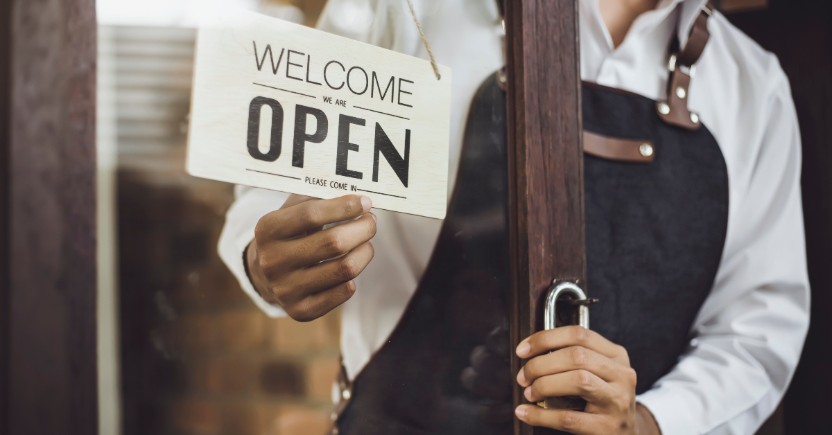 store owner turning open sign broad