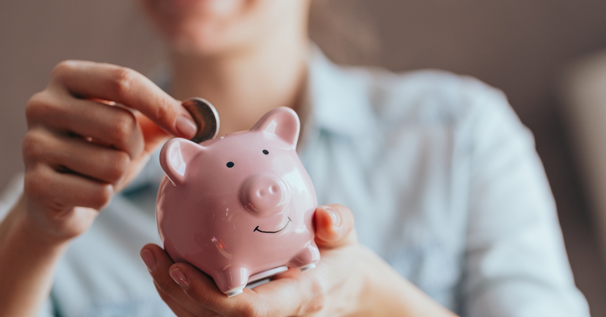 hands hold a pink piggy bank