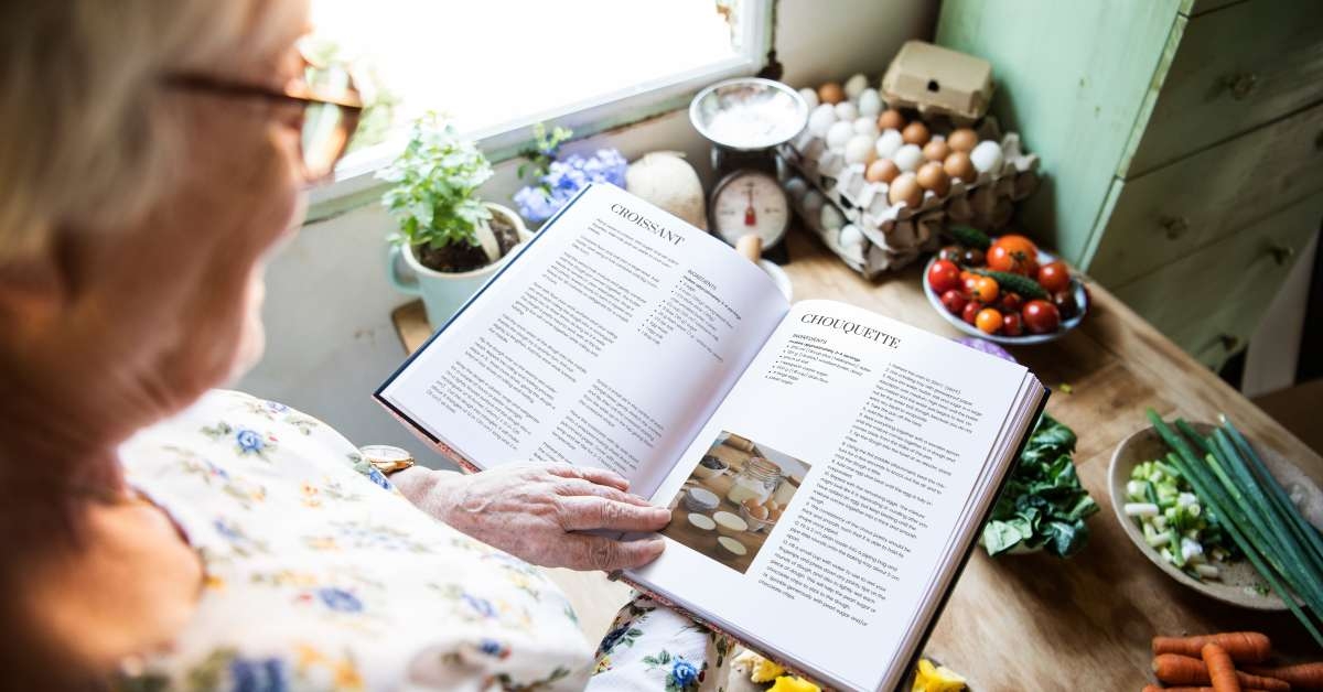 elderly woman reading a cookbook