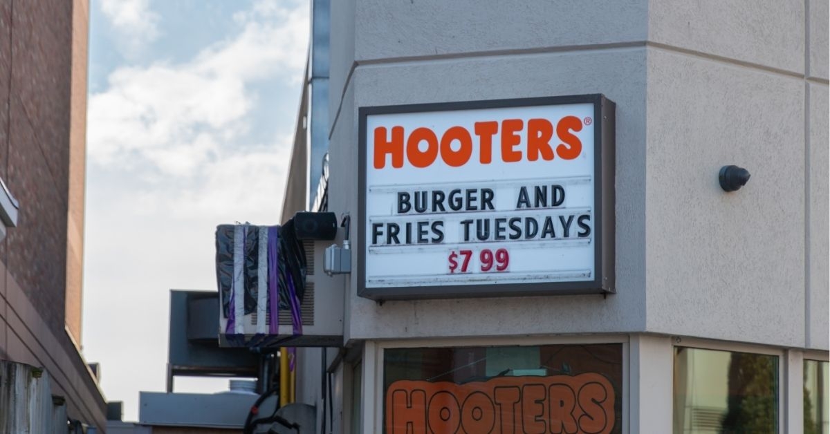Close-up of a Hooters restaurant sign displaying a promotion for a burger and fries 
