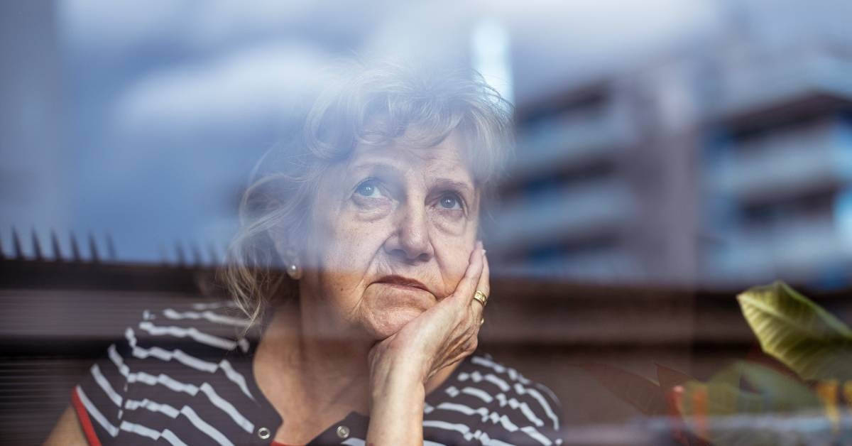 Portrait of senior woman looking through window  