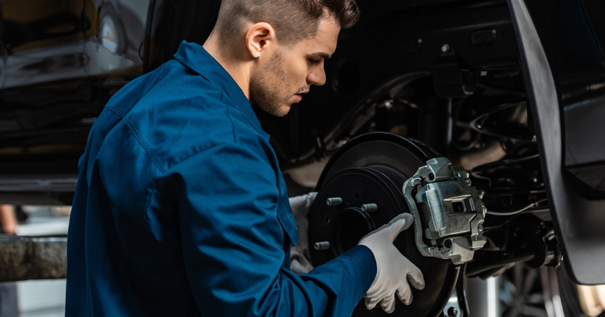 mechanic installing disc brakes on raised car
