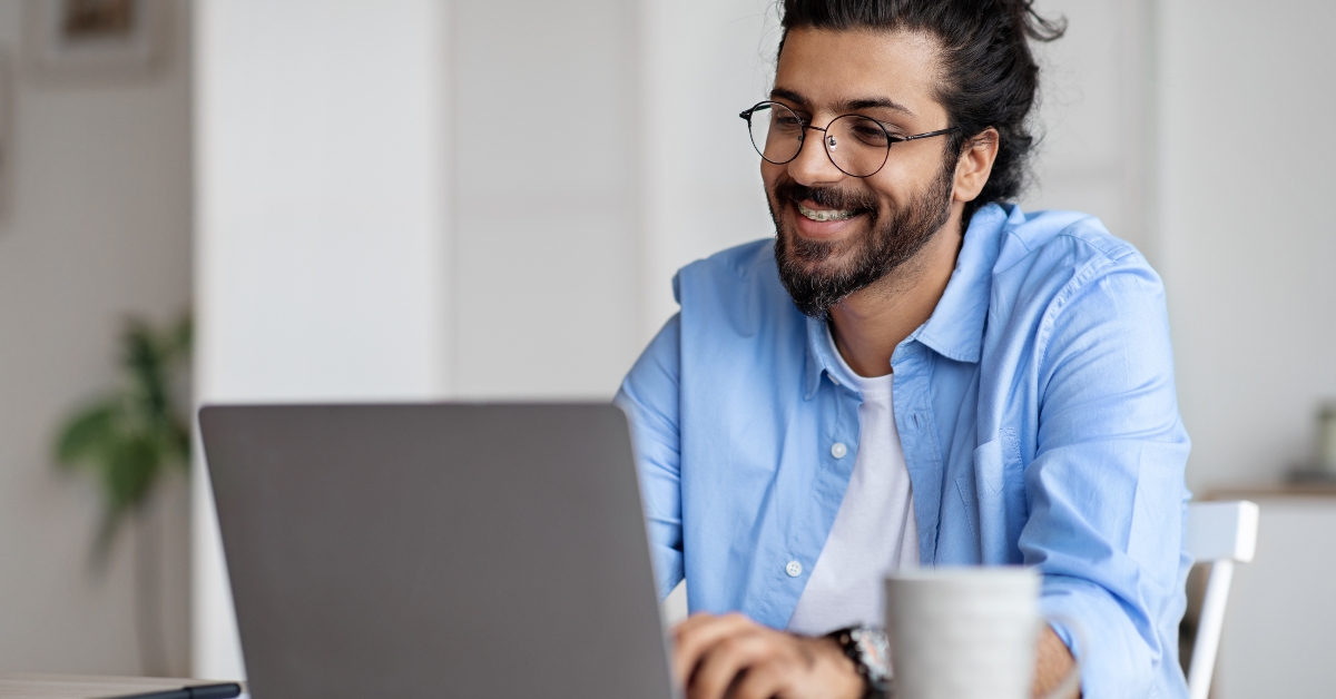 Smiling Indian Writer Using Laptop Computer