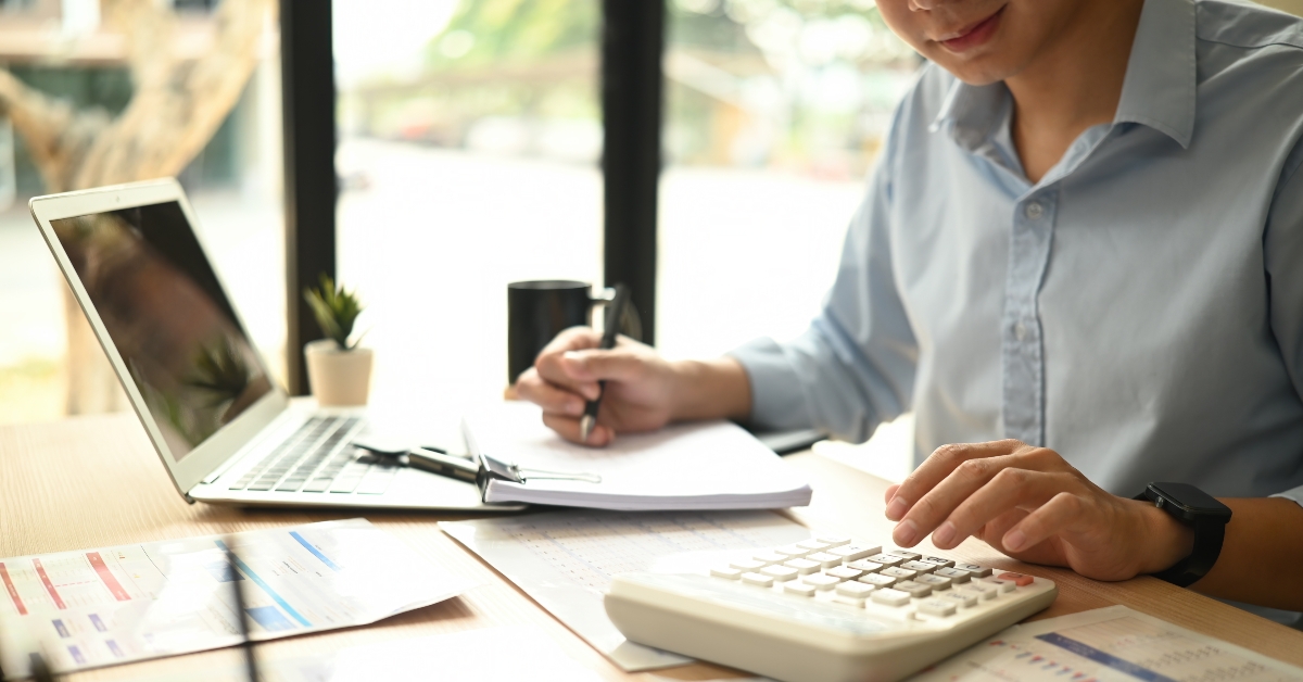 man using a calculator to evaluate financial charts