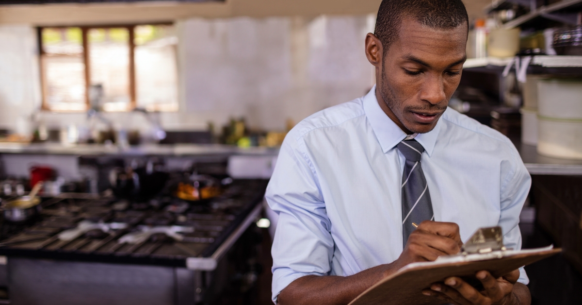 man using clipboard in commercial kitchen
