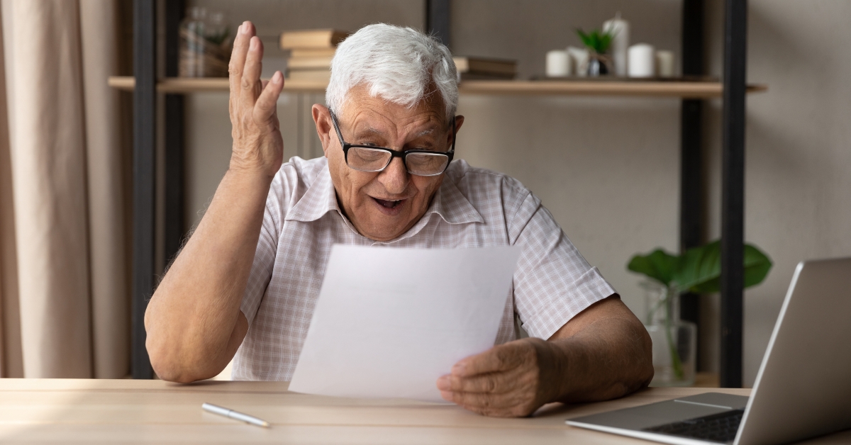 retired man in eyewear looking through paper document