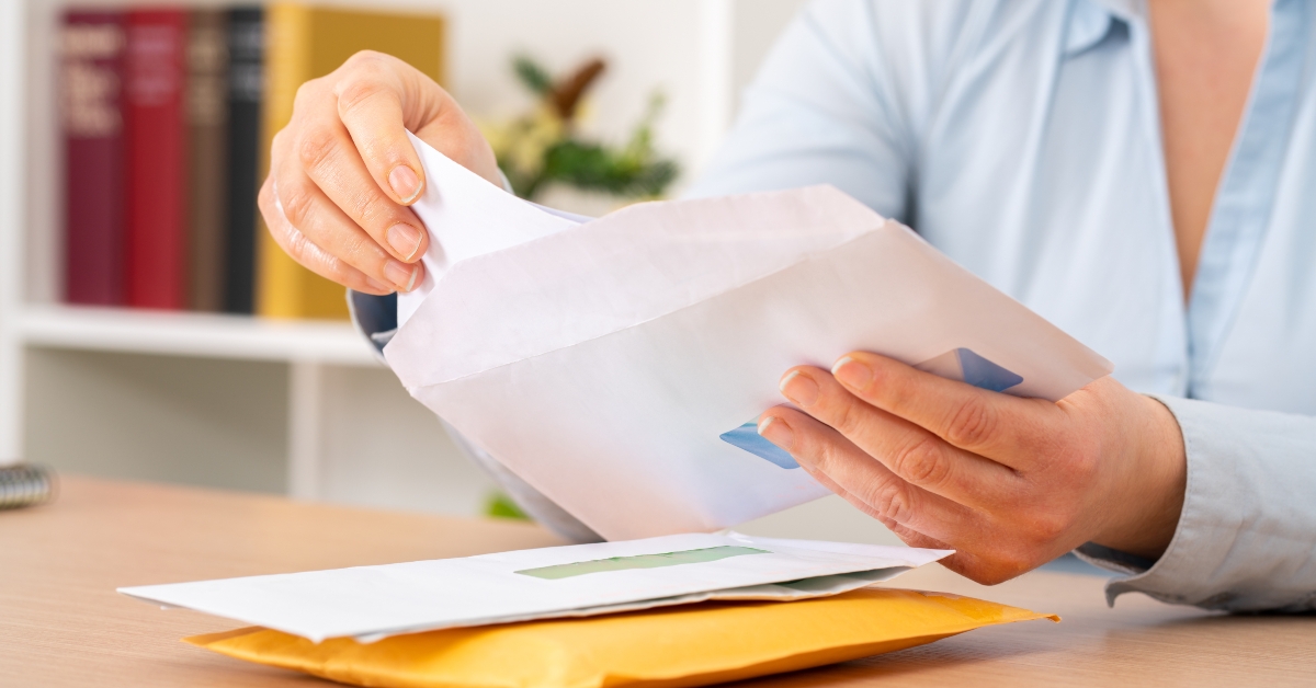 woman hands putting a letter inside an envelope