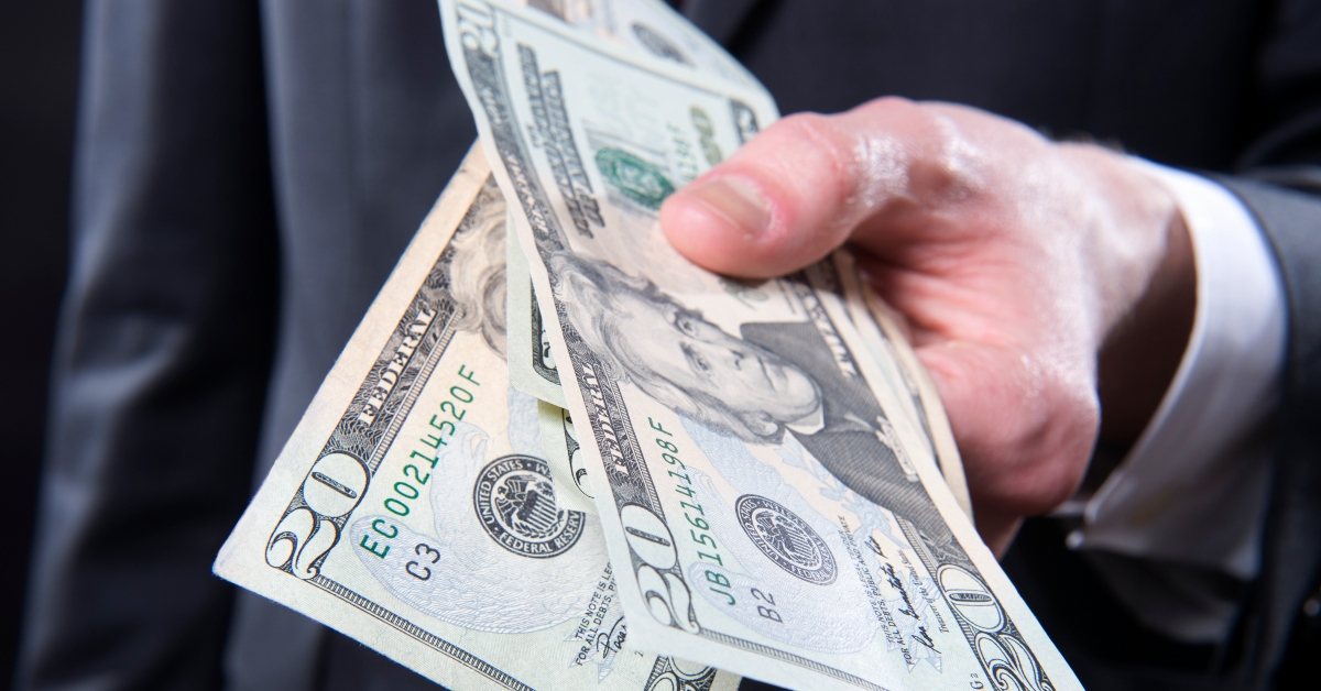 Closeup of man in suit offering cash