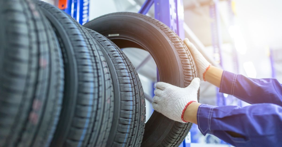 Close-up of a mechanic grabbing a car tire from a stack of tires