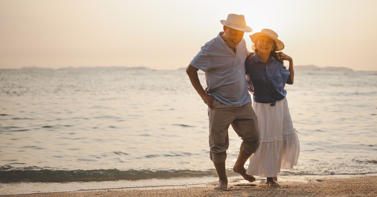 Older couple walking on the beach at sunset