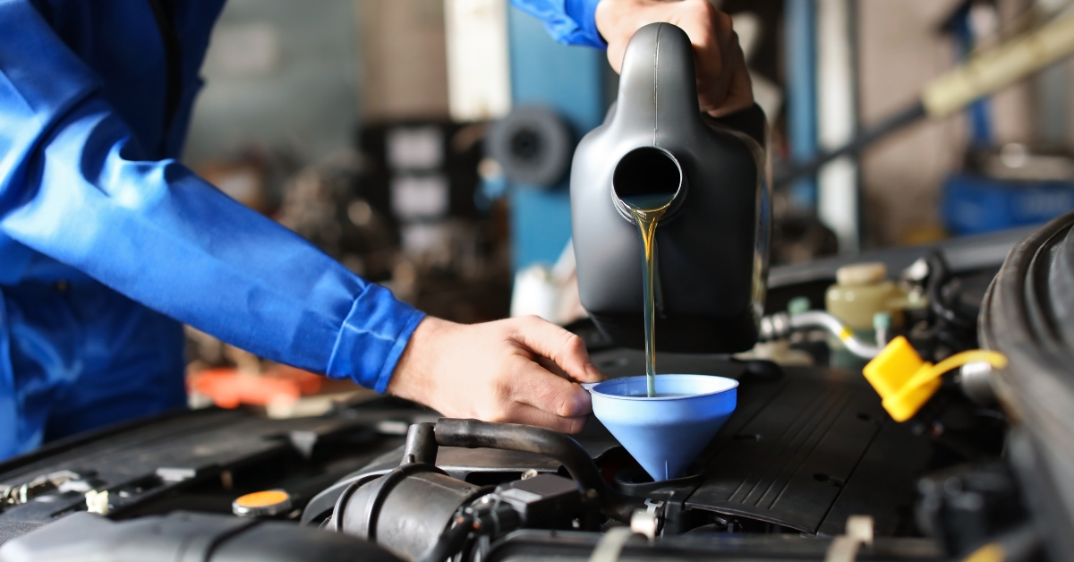 Male mechanic refilling car oil in service center