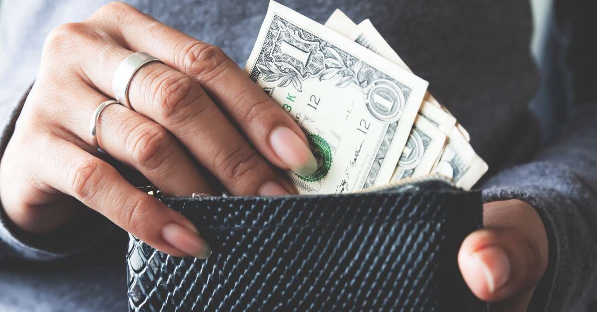 paper currency in wallet with woman