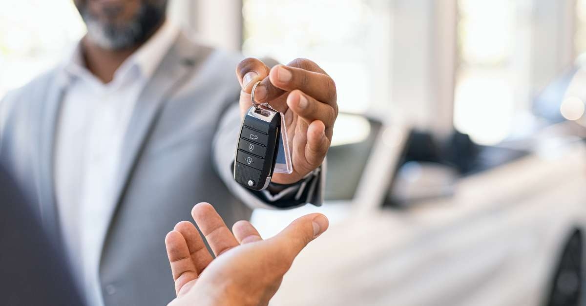 salesman giving new car keys to customer