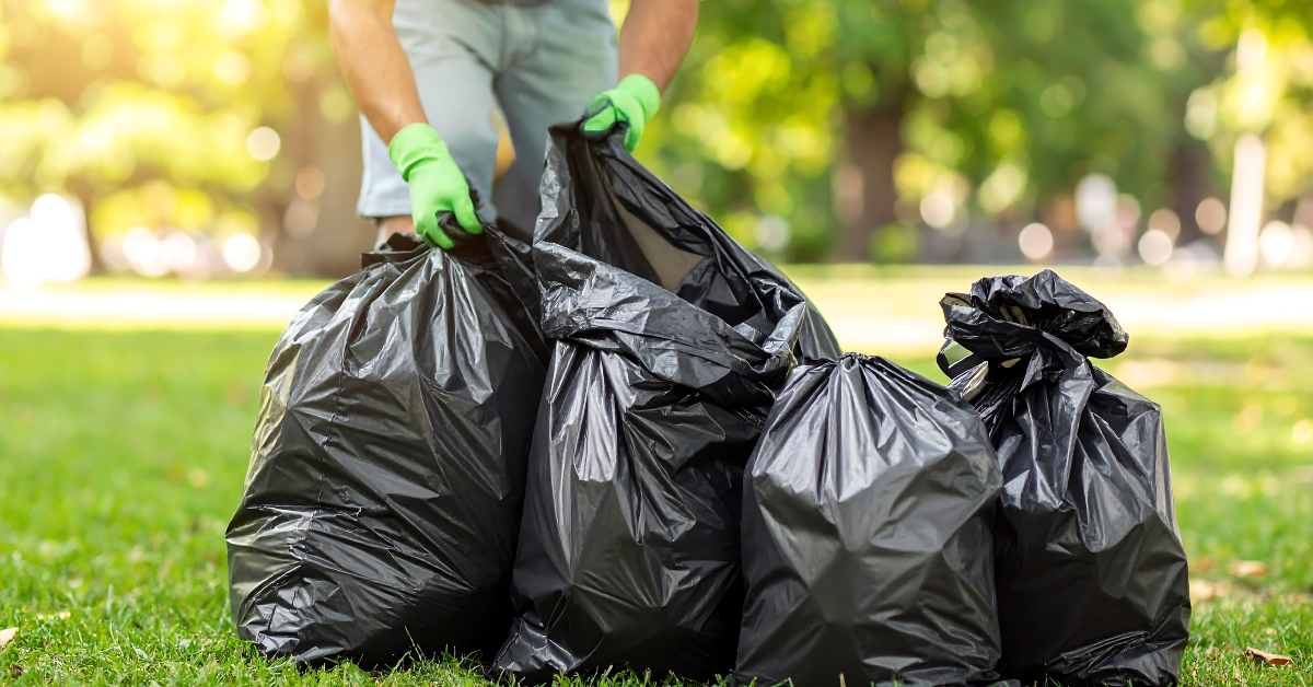 person gathers multiple black trash bags