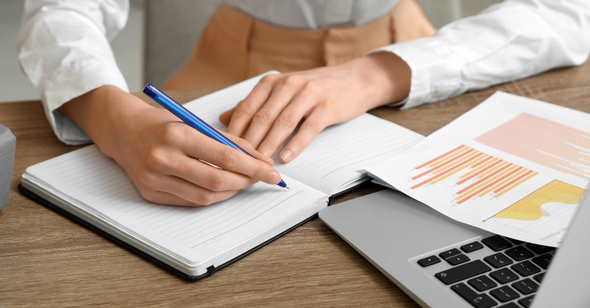 Young businesswoman writing down something while working