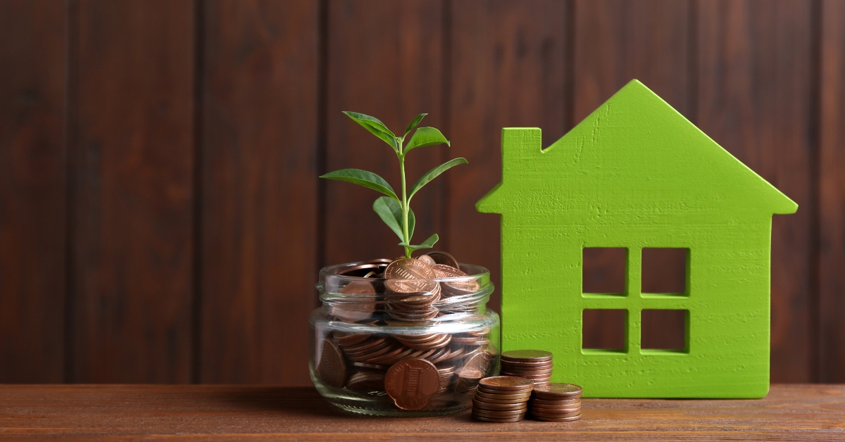 House model, jar with coins and plant on table